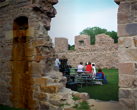 people sittiing on bleachers watching a performance in some the Queen Bee mill ruins